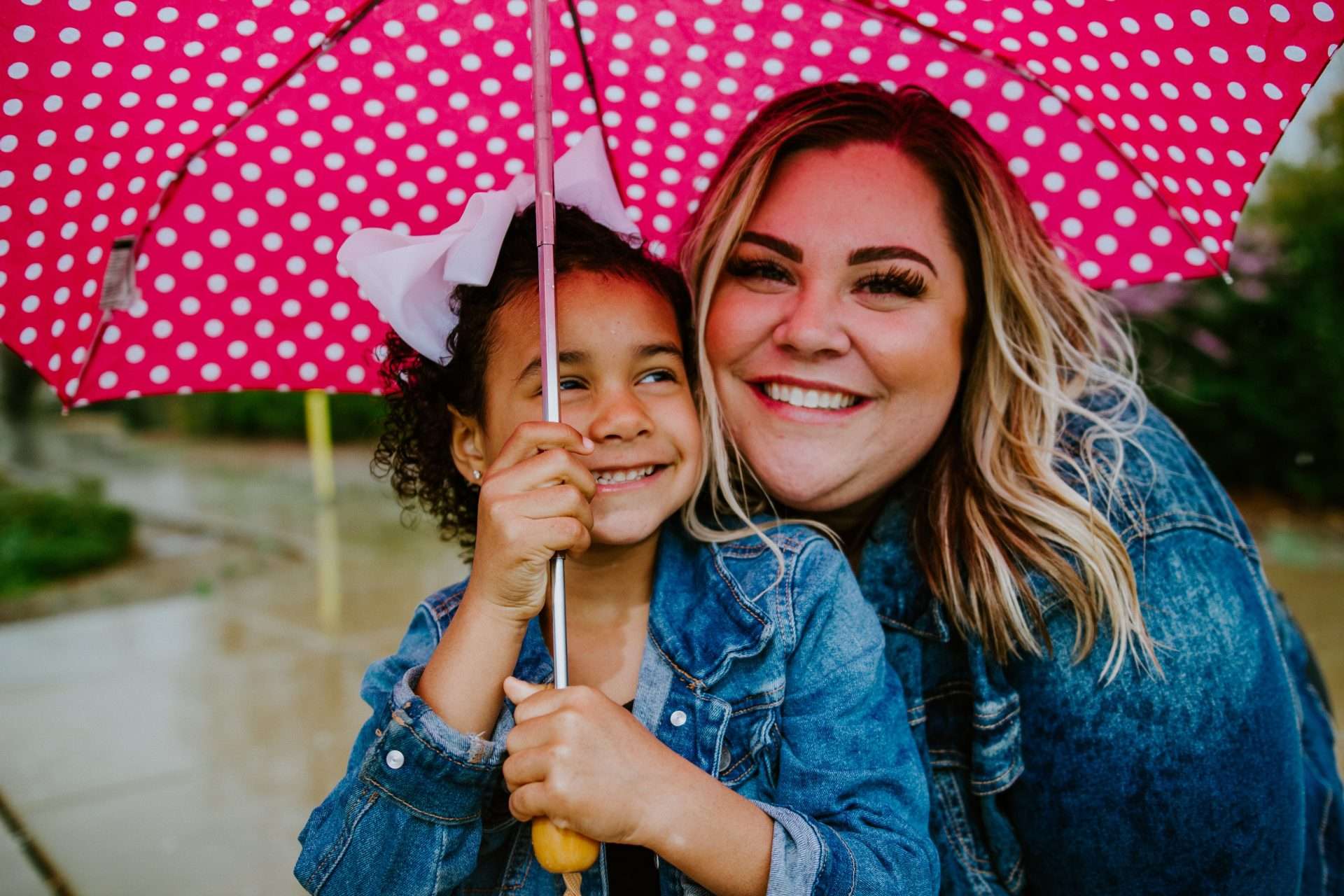 woman and child smiling under pink umbrella